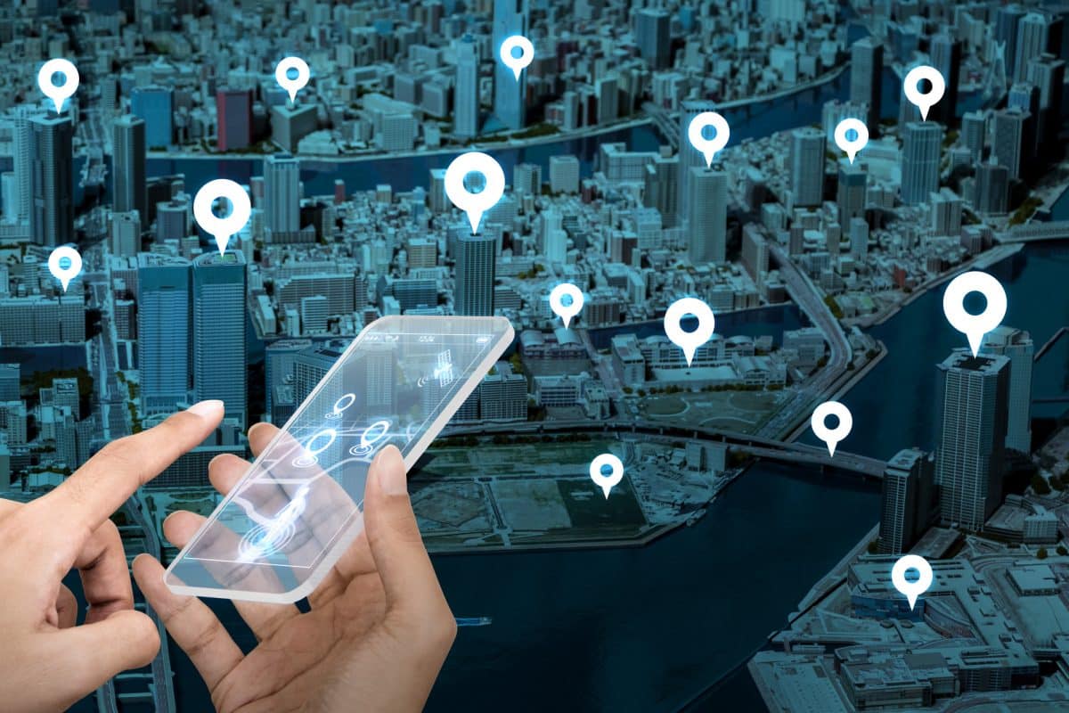 GPS Tracker With Camera Hand holding a digital device over an aerial city map with multiple location markers representing GPS tracking.